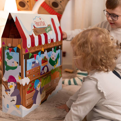 Mädchen und Junge schauen sich den aufgebauten Adventskalender im Wohnzimmer an. 