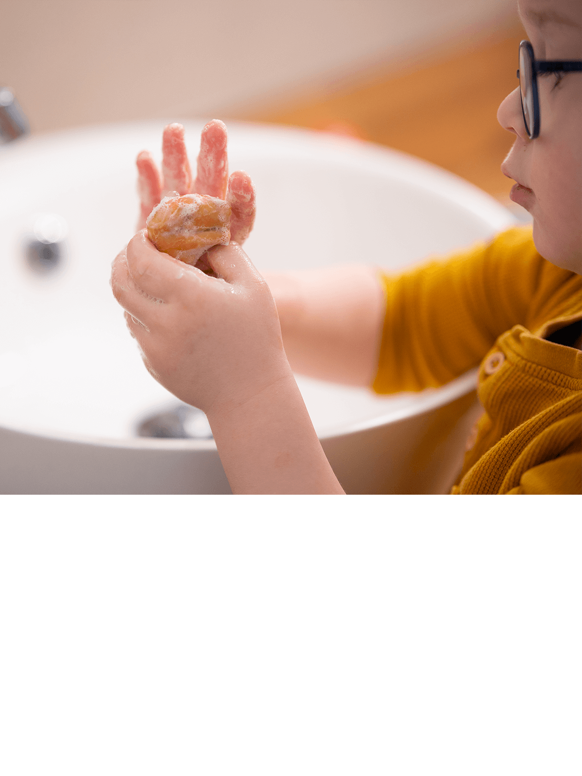 Kind mit Brille wäscht sich die Hände mit der festen Hand-Seife Pia Putzig