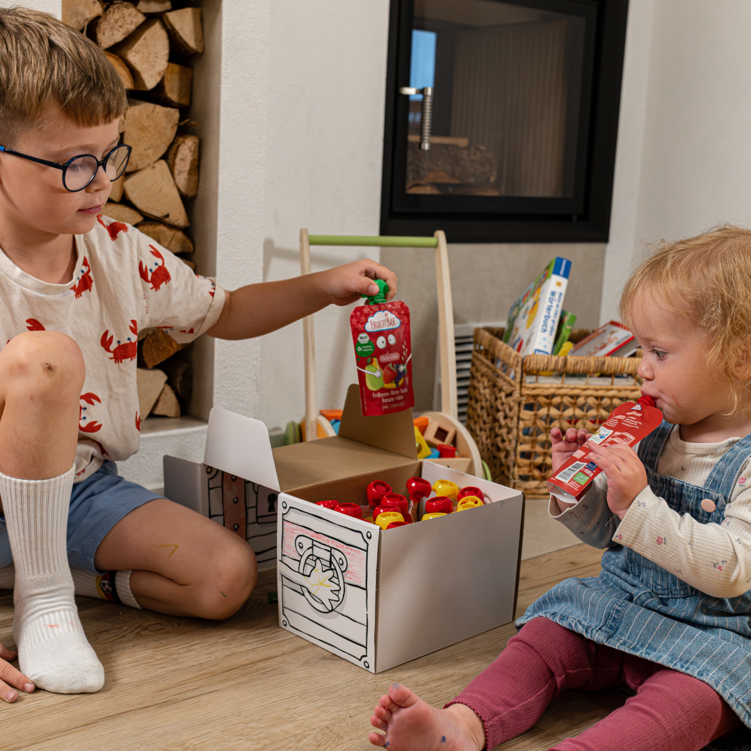 Mädchen und Junge essen Quetschies aus der Schatzkiste.
