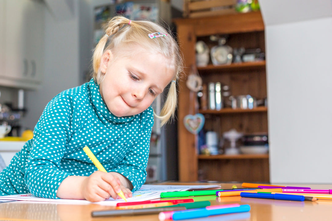 Kind mal Ausmalbild am Esstisch aus