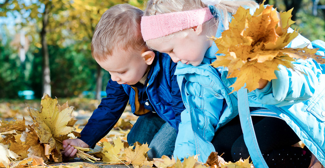 Kinder sammeln Blätter im Herbst
