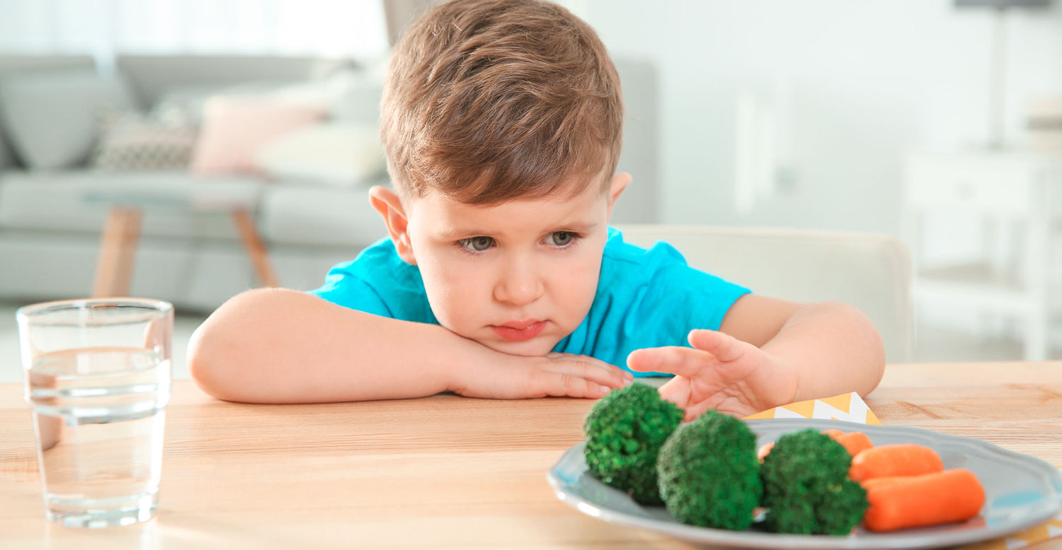 Jung guckt skeptisch auf Gemüseteller