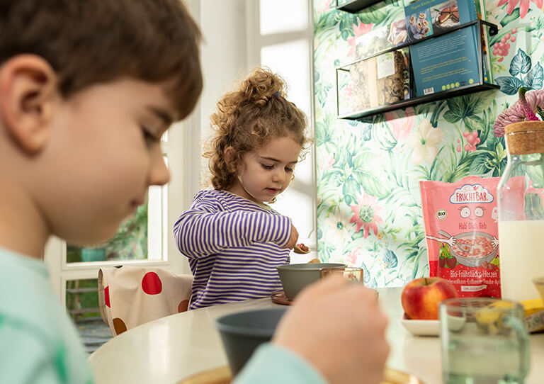 Kinder am Fruehstueckstisch mit Muesli