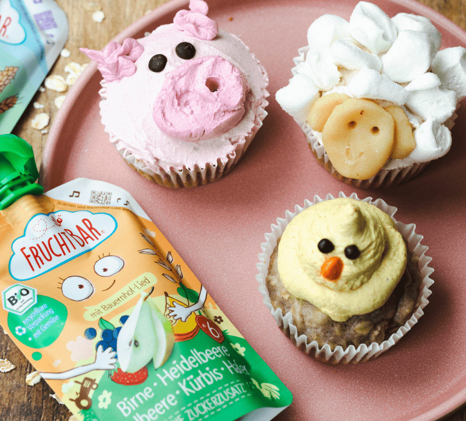 FruchtBar Quetschie mit Kinderlied zum Bauernhof-Thema neben Schwinchen- und Küken-Cupcakes